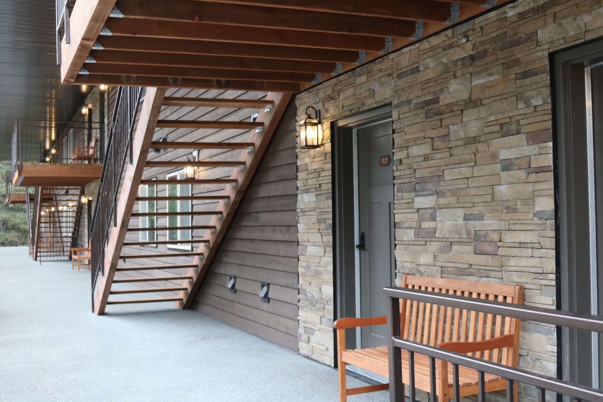 Exterior of building with stone wall, stairs, and a bench.