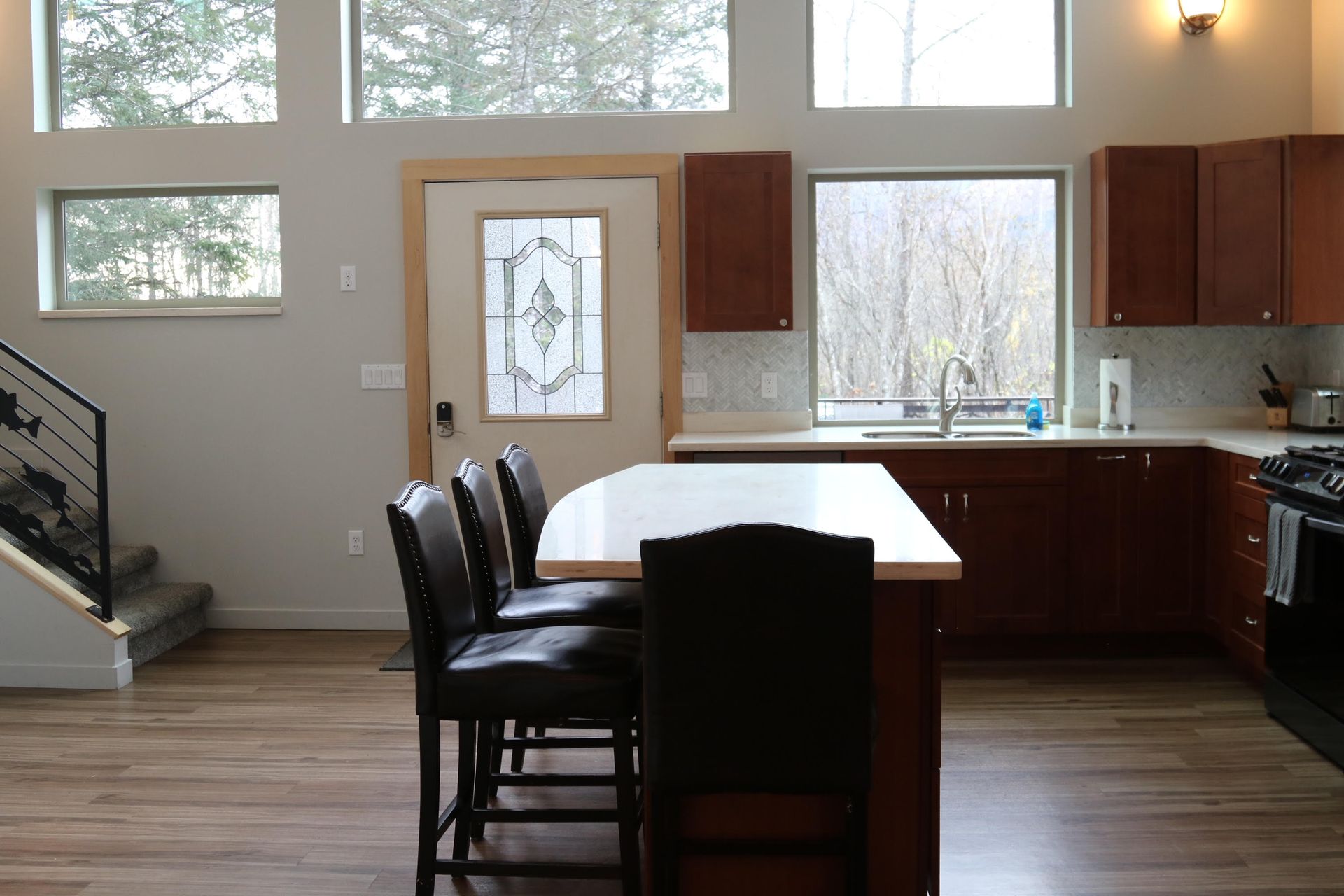 Kitchen with dark wood cabinets, a white countertop island, and tall windows.