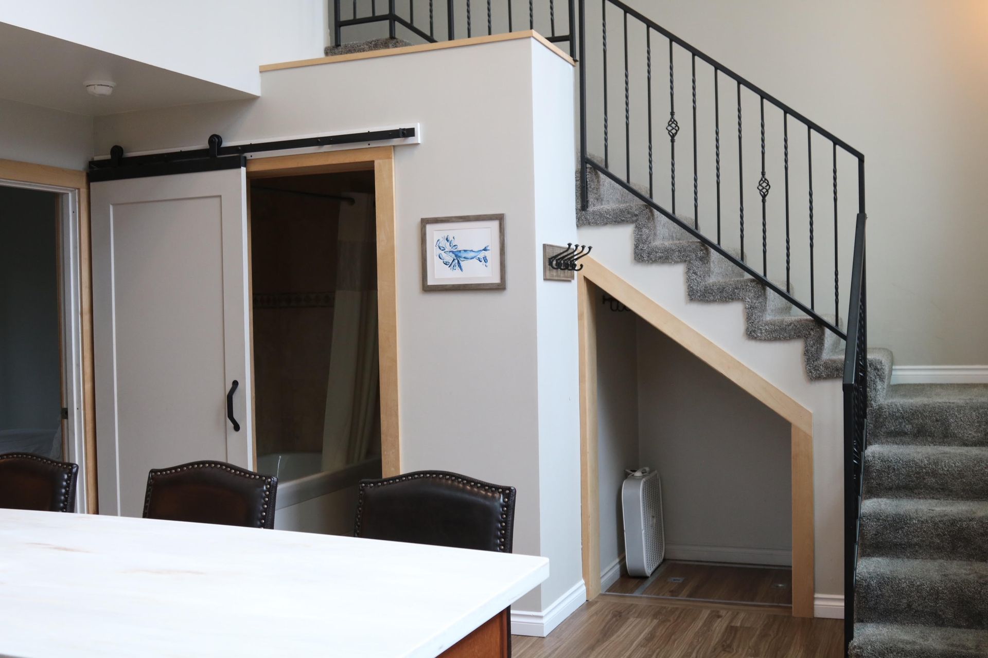 Interior with stairs, bathroom with sliding door, and under-stair storage. Light wood trim, neutral walls.
