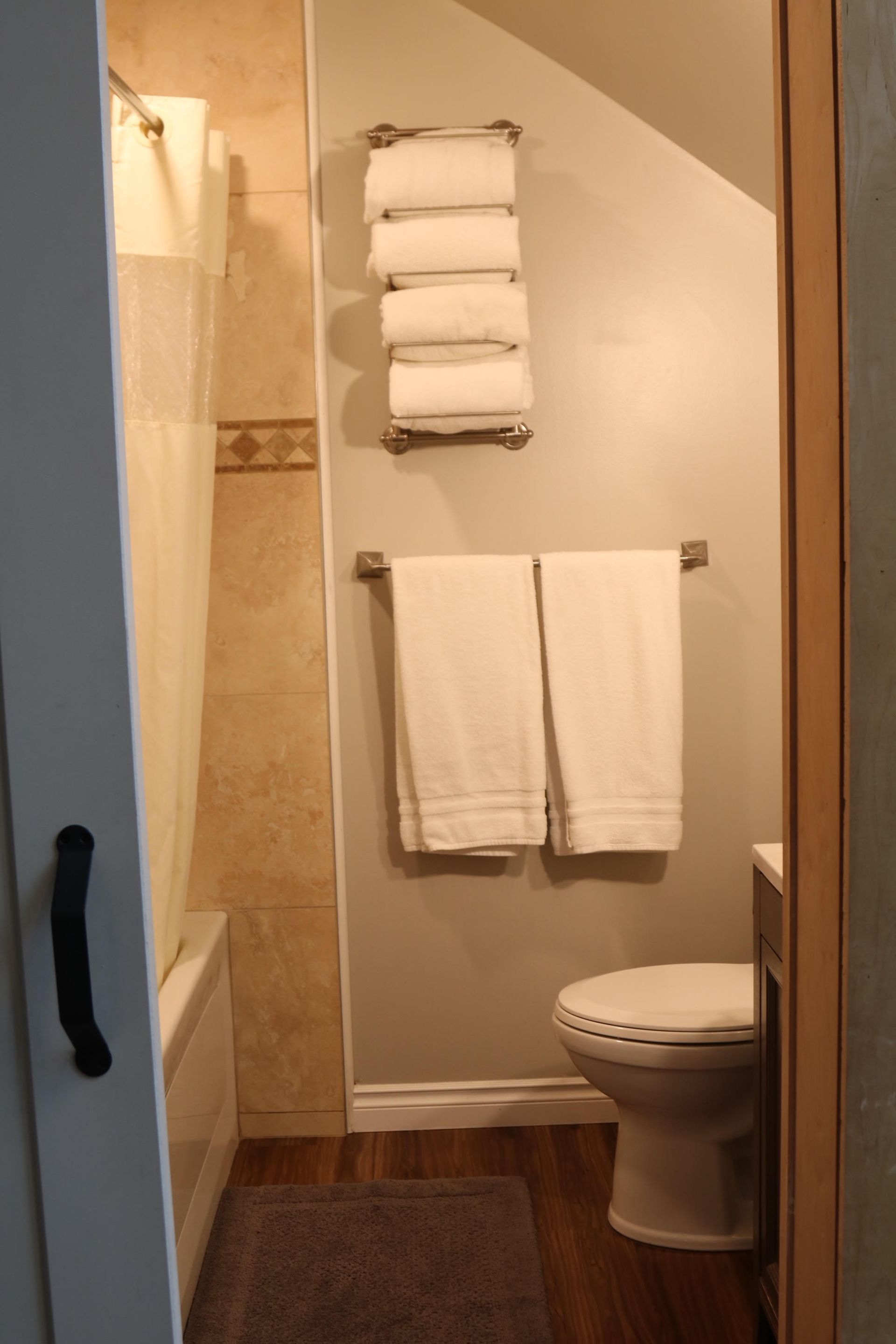 Bathroom interior with white towels on racks, a toilet, and a bathtub with a curtain.