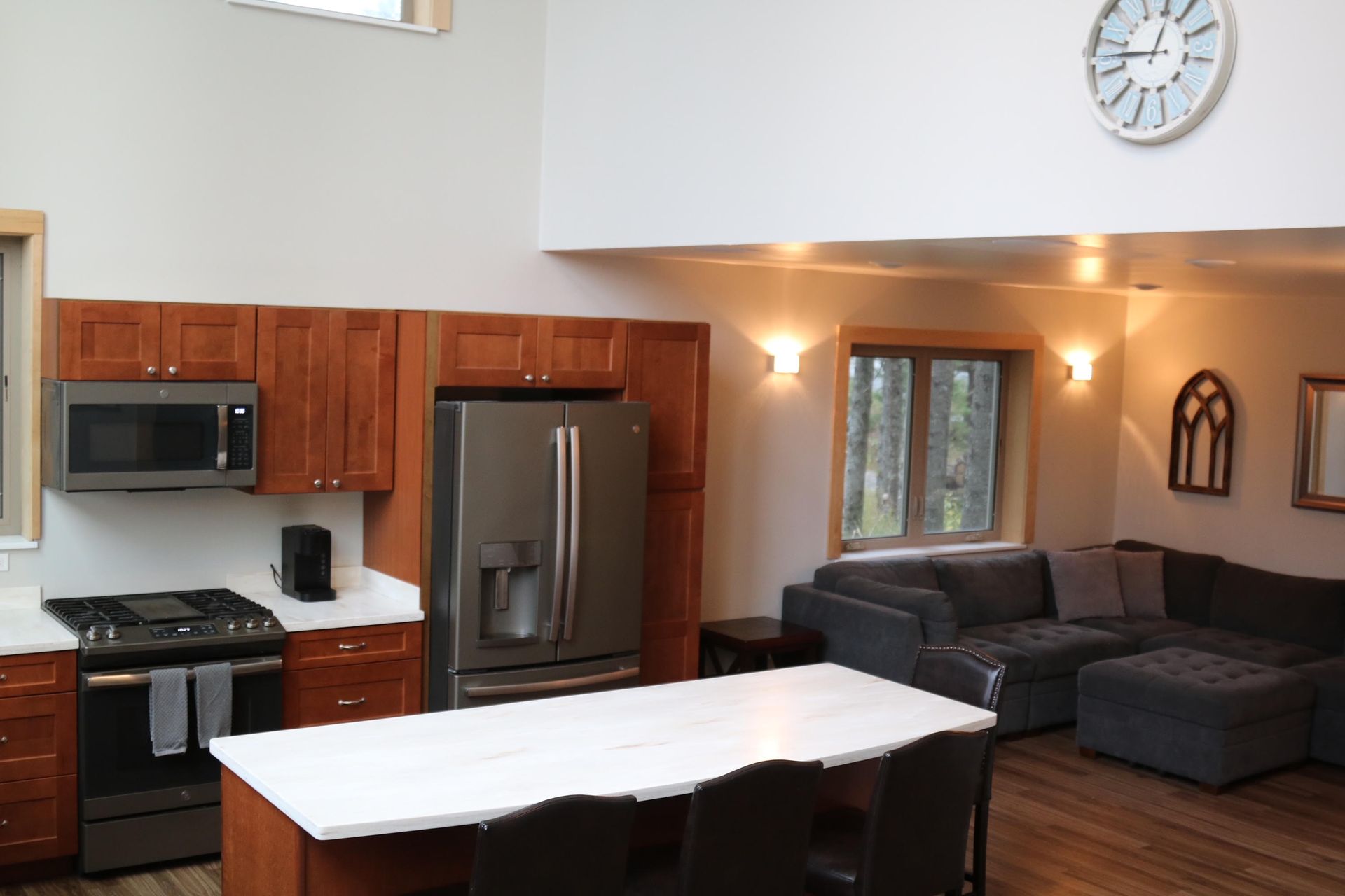 Kitchen with dark wood cabinets, stainless steel appliances, and white island and countertop.