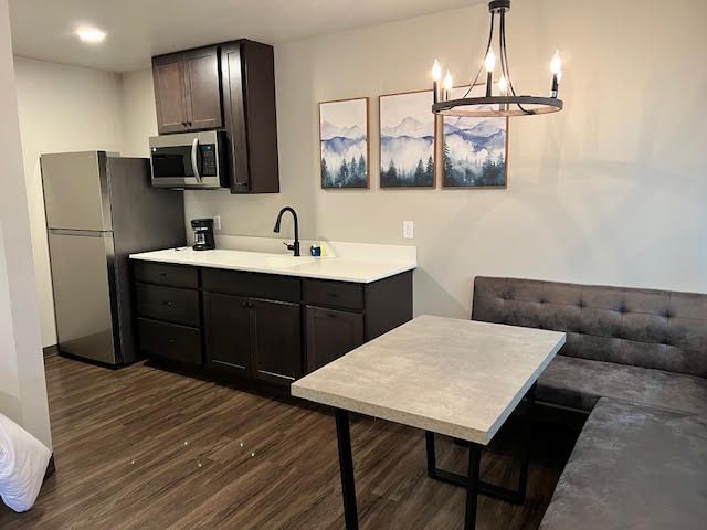Kitchenette with dark cabinets, stainless steel appliances, and a small dining table.