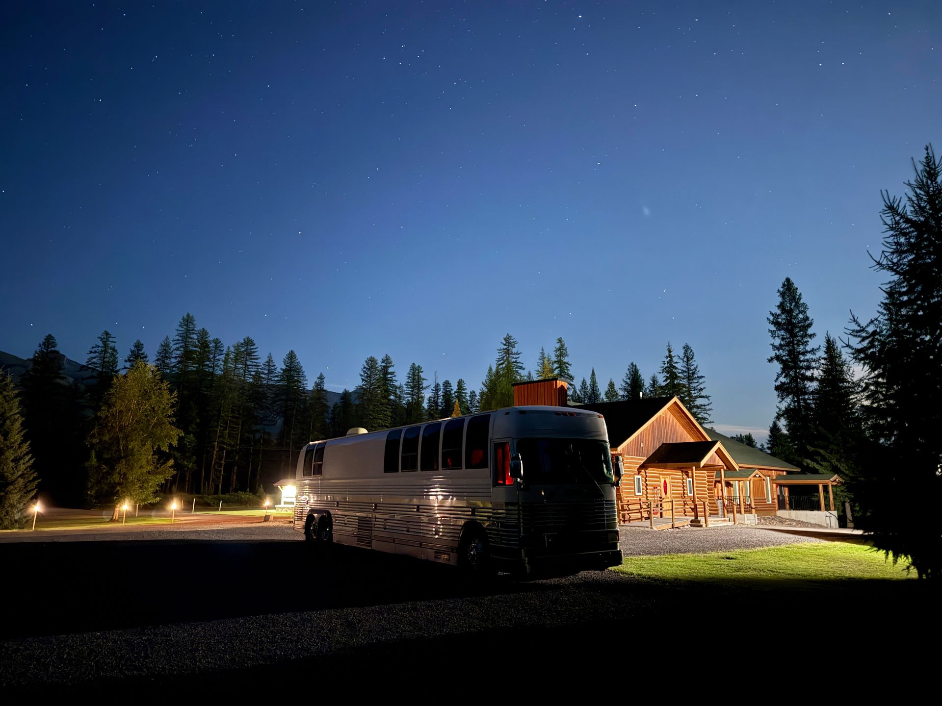RV parked in front of a wood cabin at night under a starry sky.