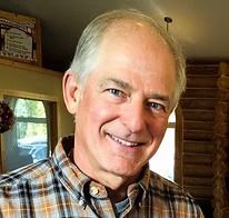 Smiling older man in plaid shirt, outdoors.