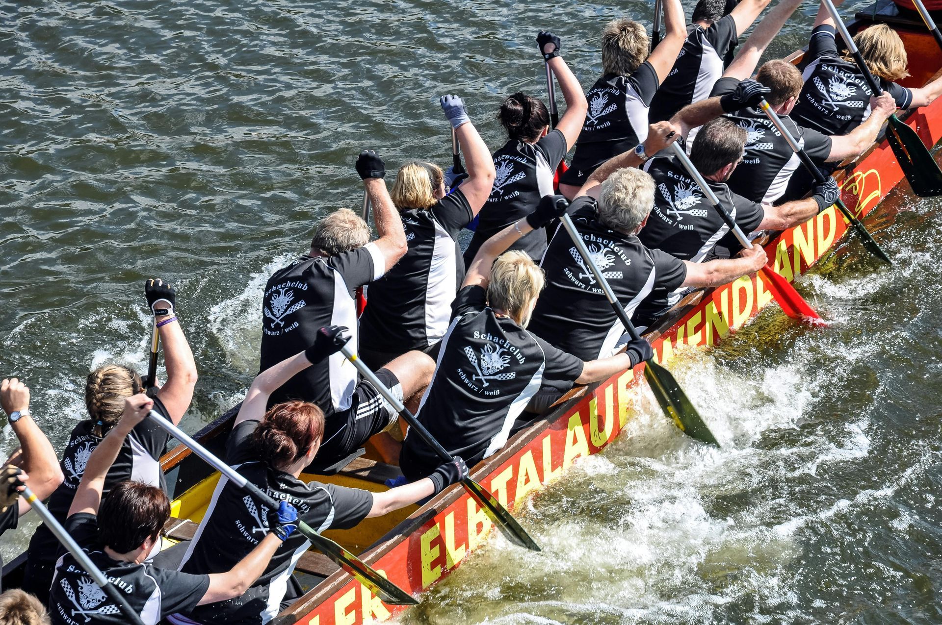 Teamwork - A group of people are rowing a boat in the water.