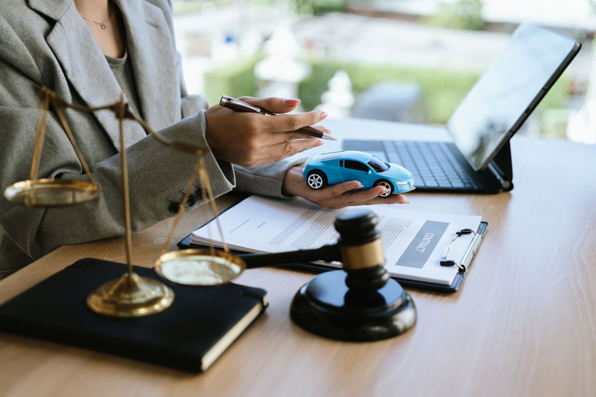 A lawyer signing a car contract with a gavel and a toy car on the desk.