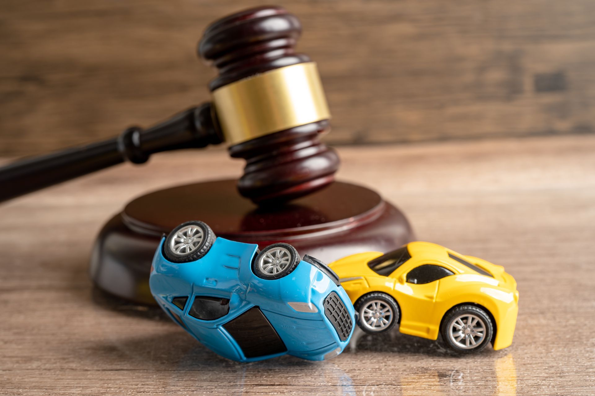 Toy cars in a crash scene placed beside a judge’s gavel representing an auto accident case.