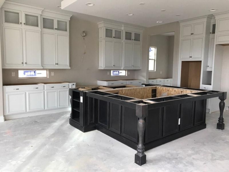 A kitchen with white cabinets and a black island in the middle.