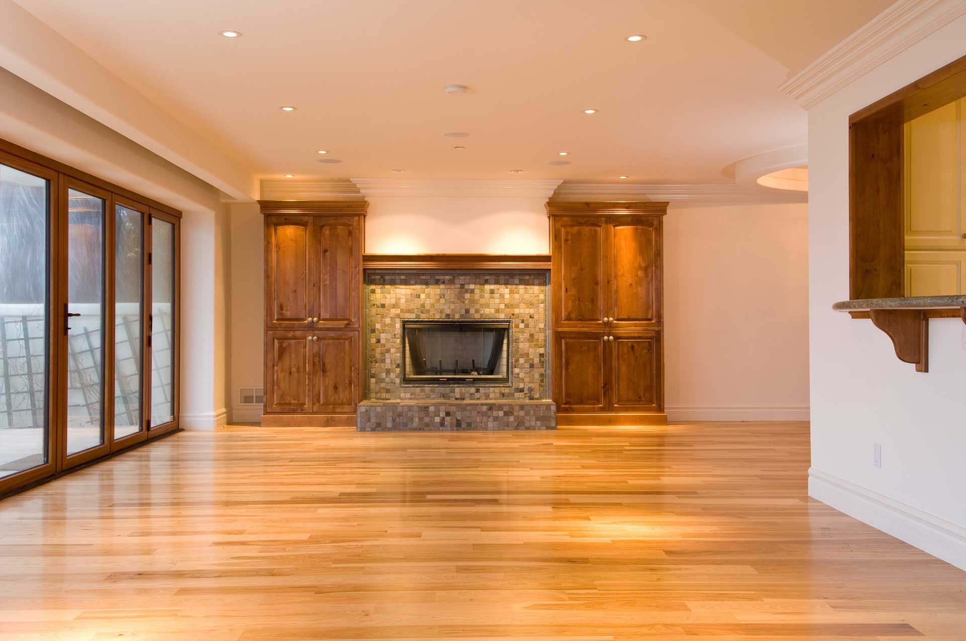 An empty living room with hardwood floors and a fireplace