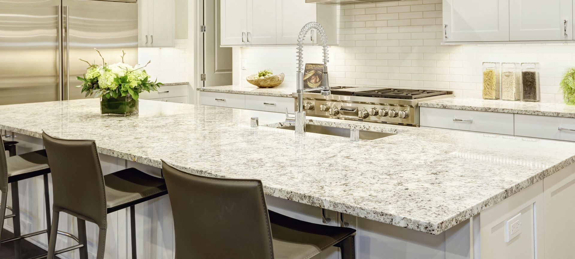 A kitchen with granite counter tops , stainless steel appliances , and white cabinets.