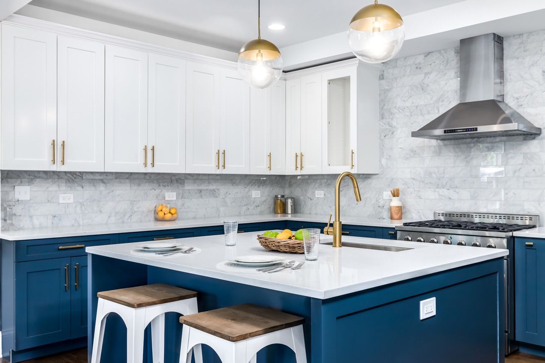 A kitchen with blue cabinets and white counter tops and a large island.