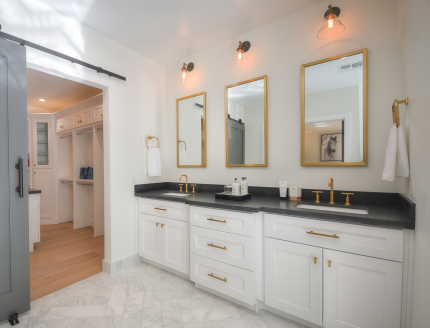A bathroom with two sinks , two mirrors and a sliding barn door.