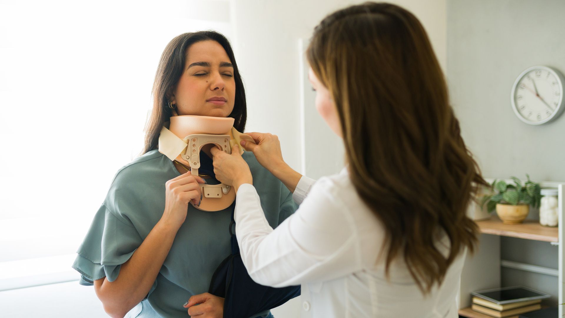 A doctor gently applying a cervical collar to a patient with neck pain following an accident.