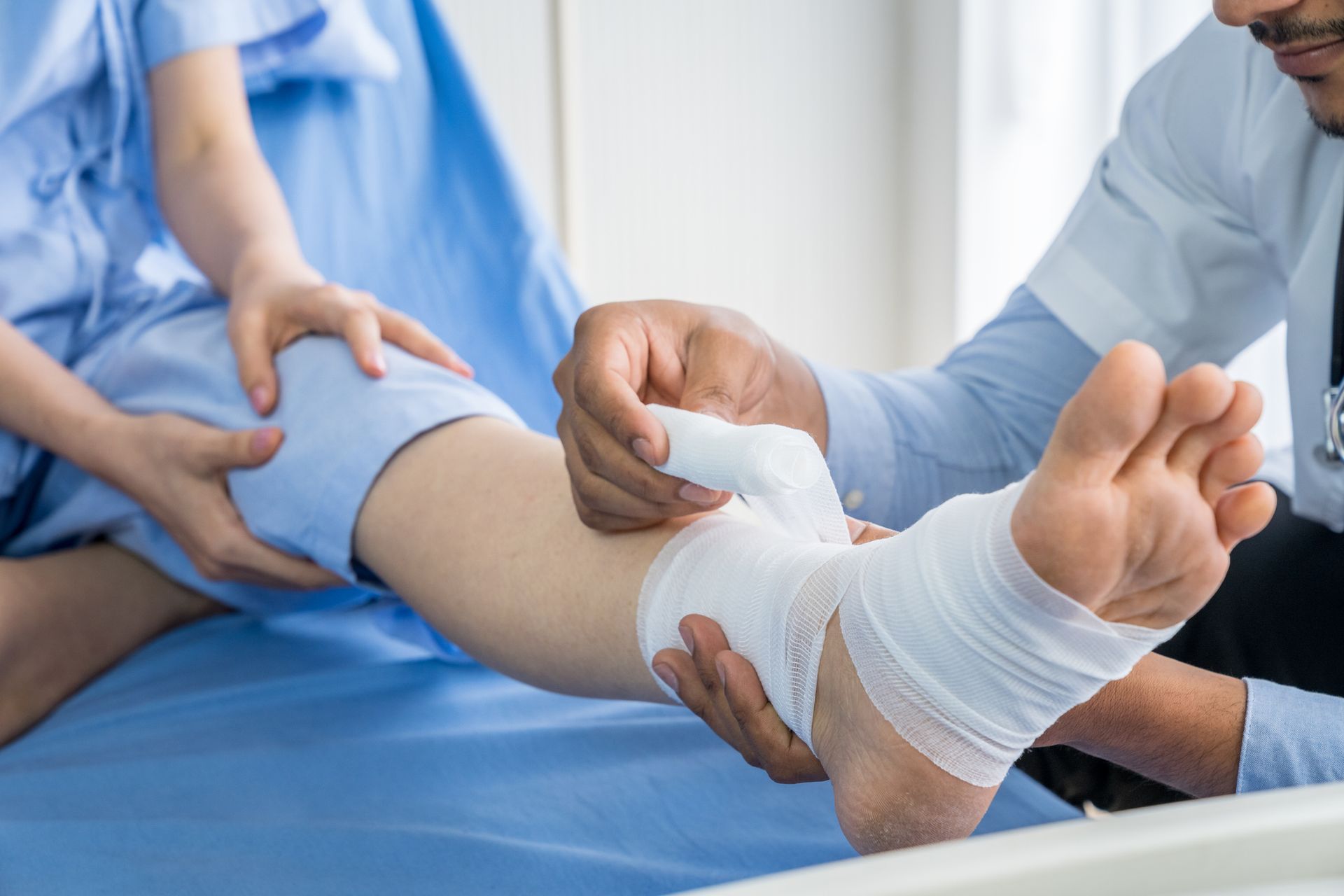 Doctor is bandaging upper limb of patient on the hospital bed