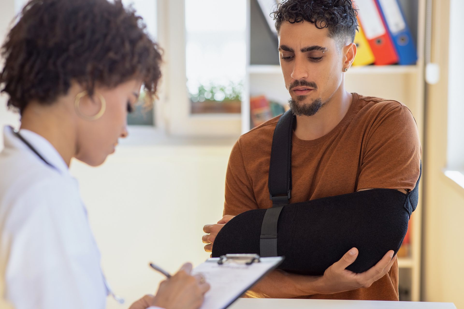 A man with a fractured arm is engaged in a conversation with a nurse at an accident injury clinic.