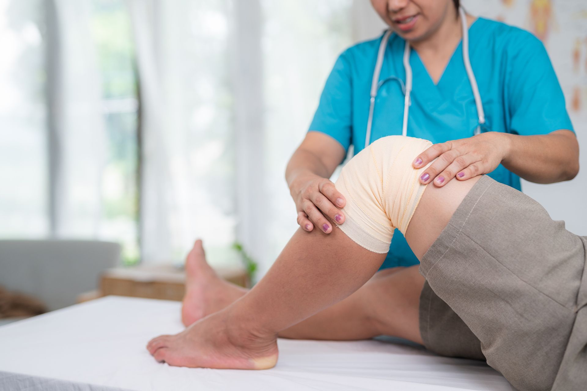 Nurse examining patient with knee problems in clinic.