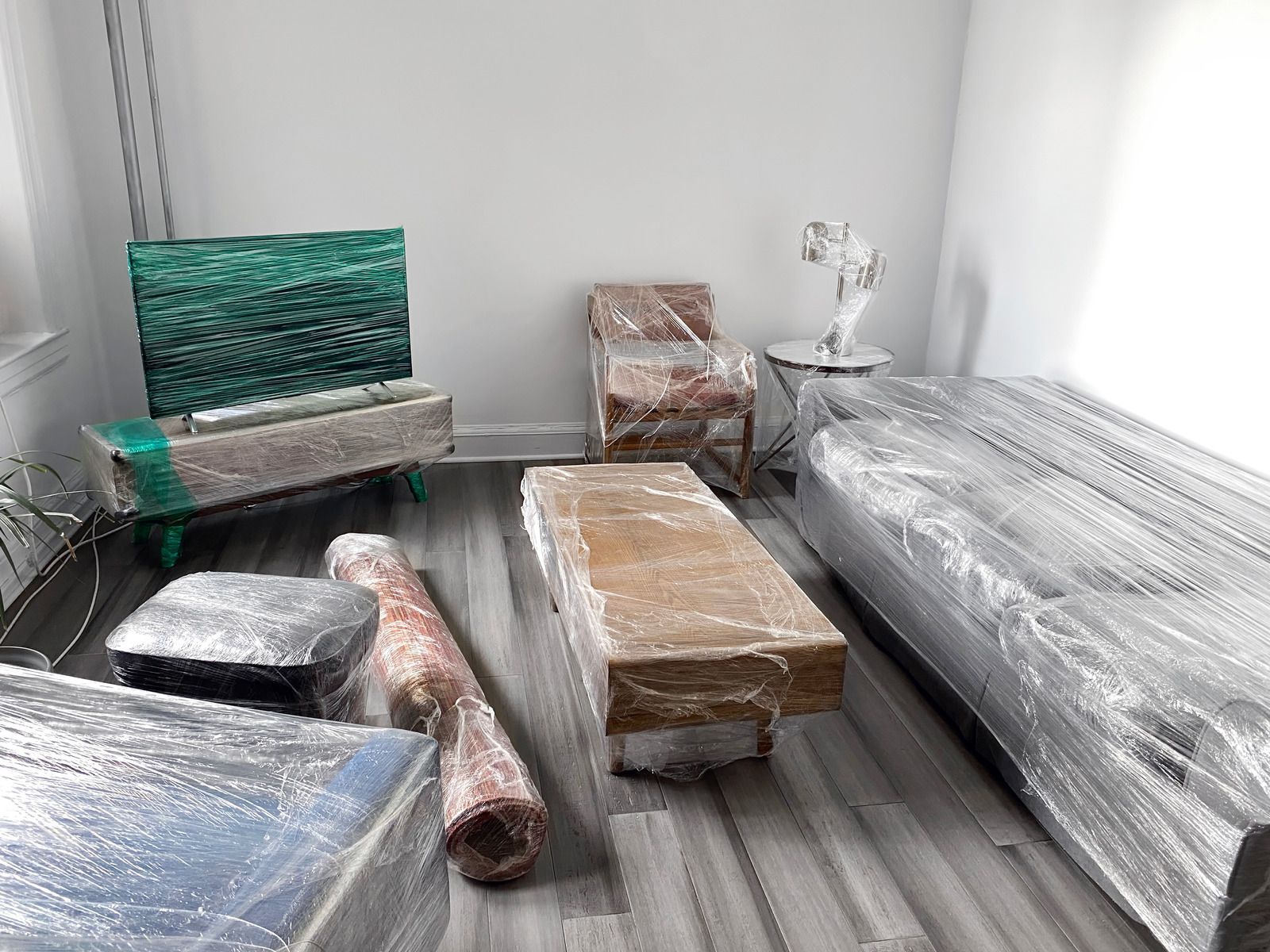 A living room filled with furniture wrapped in plastic.