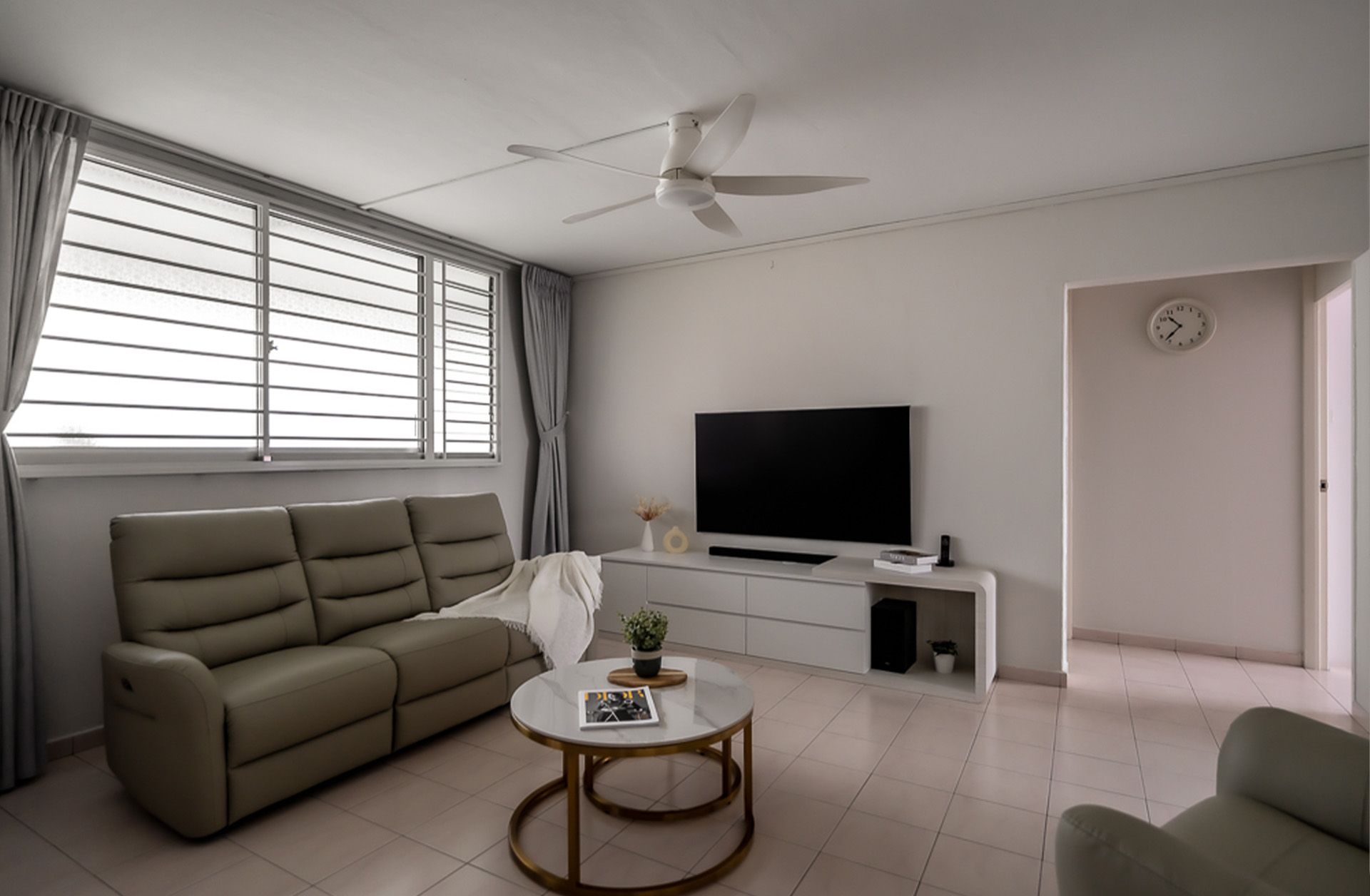 A living room with a couch , table , television and ceiling fan.