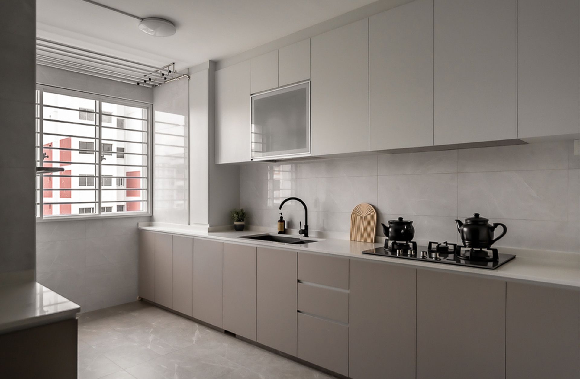 A kitchen with white cabinets , a sink , a stove , and a window.