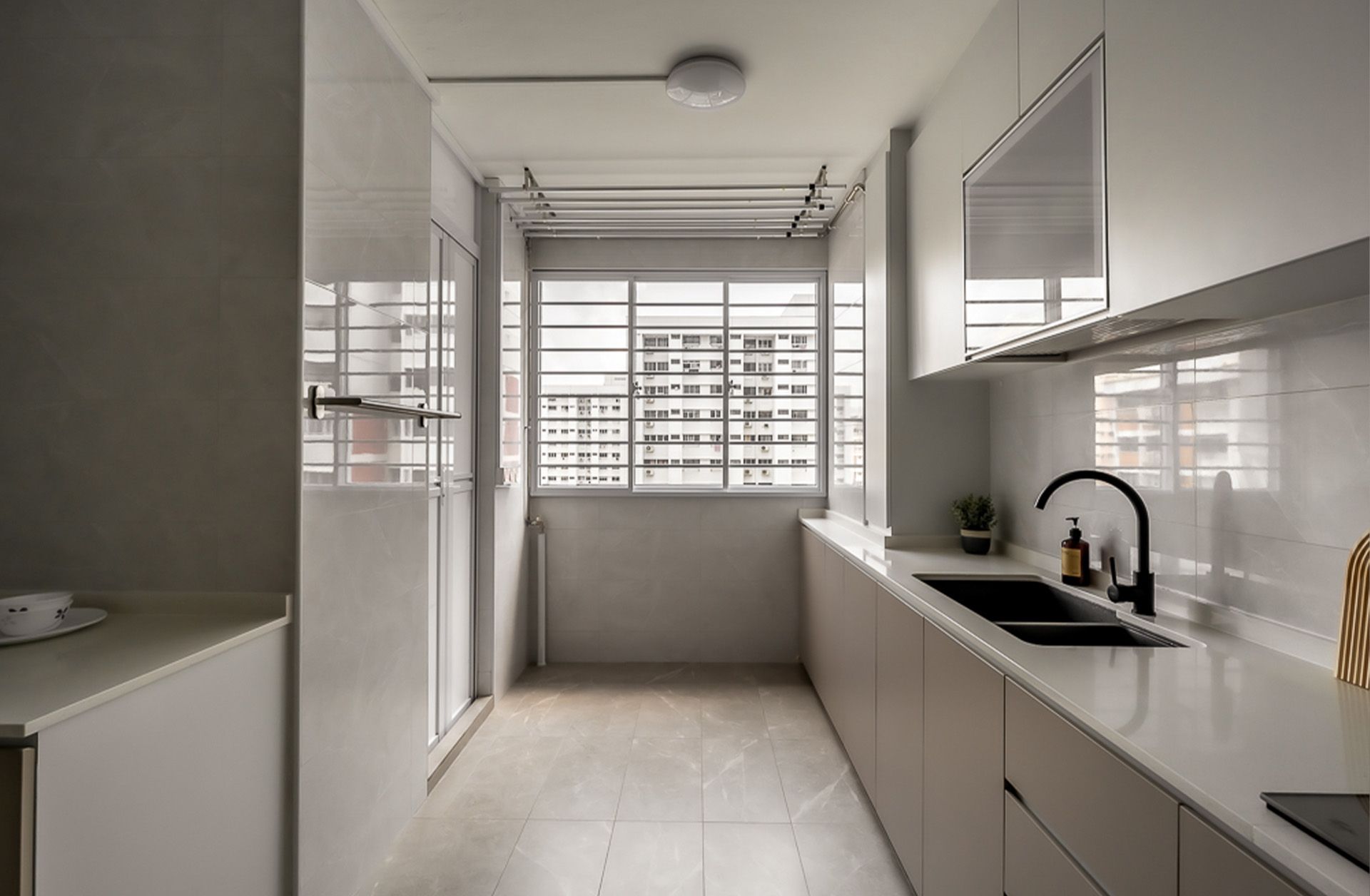 A kitchen with white cabinets , a sink , and a window.