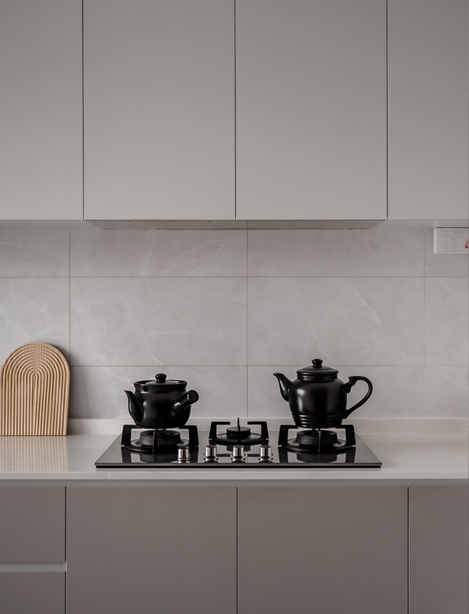 There are two pots and a teapot on the stove in the kitchen.