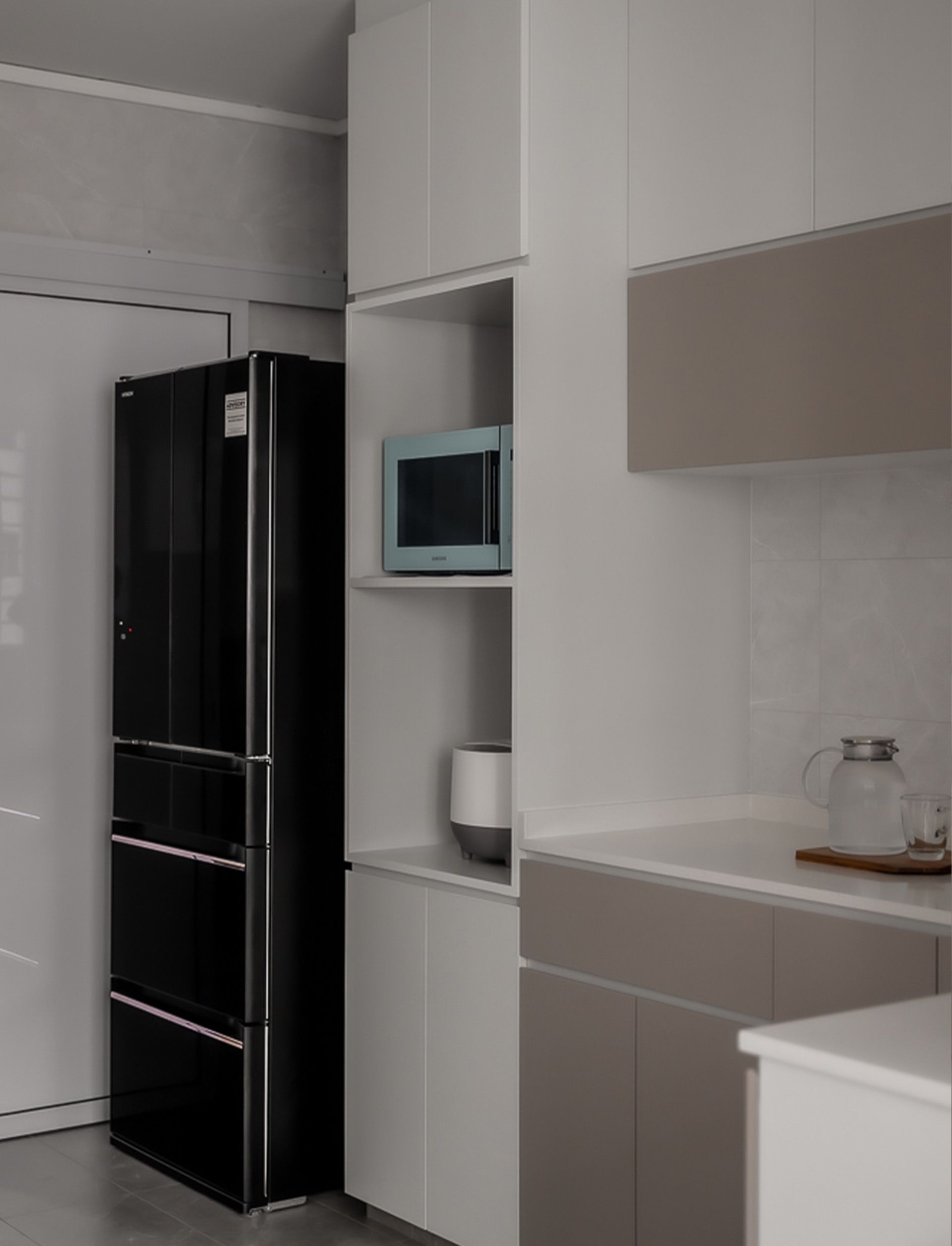 A kitchen with a black refrigerator and a microwave.