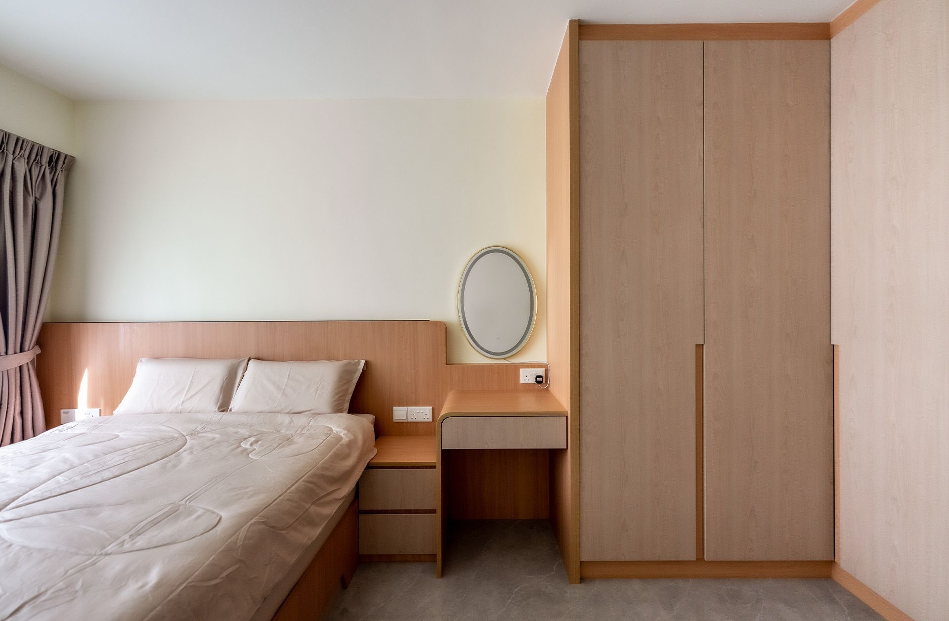 A bedroom with a bed , dresser , mirror and wardrobe.