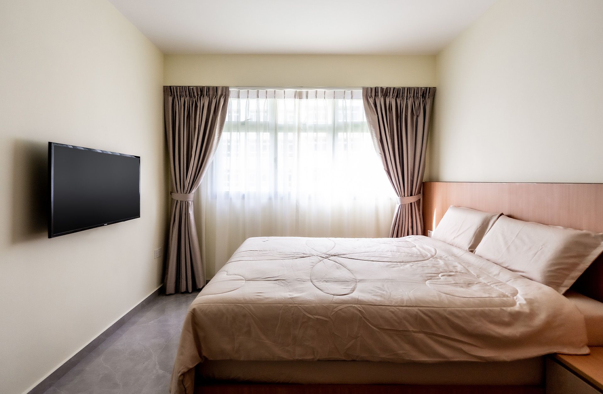 A bedroom with a large bed and a flat screen tv on the wall.