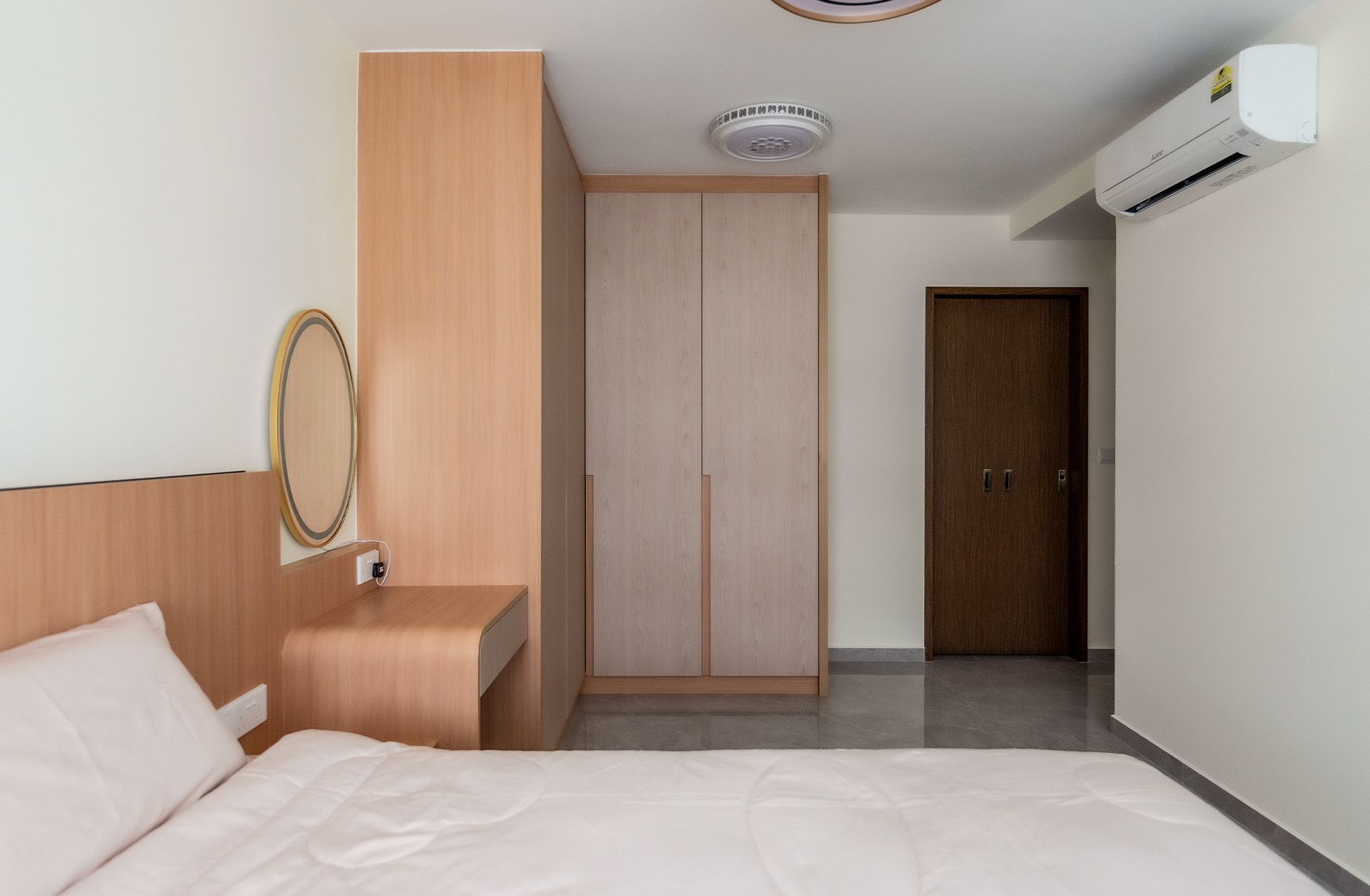 A bedroom with a bed , dresser , mirror and wardrobe.