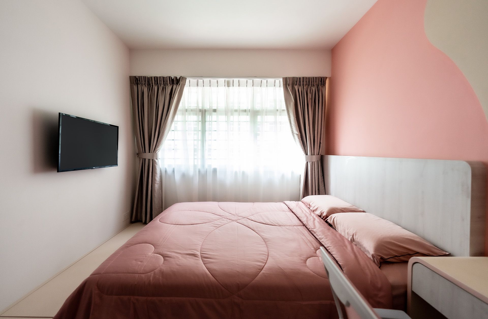 A bedroom with a large bed and a flat screen tv on the wall.