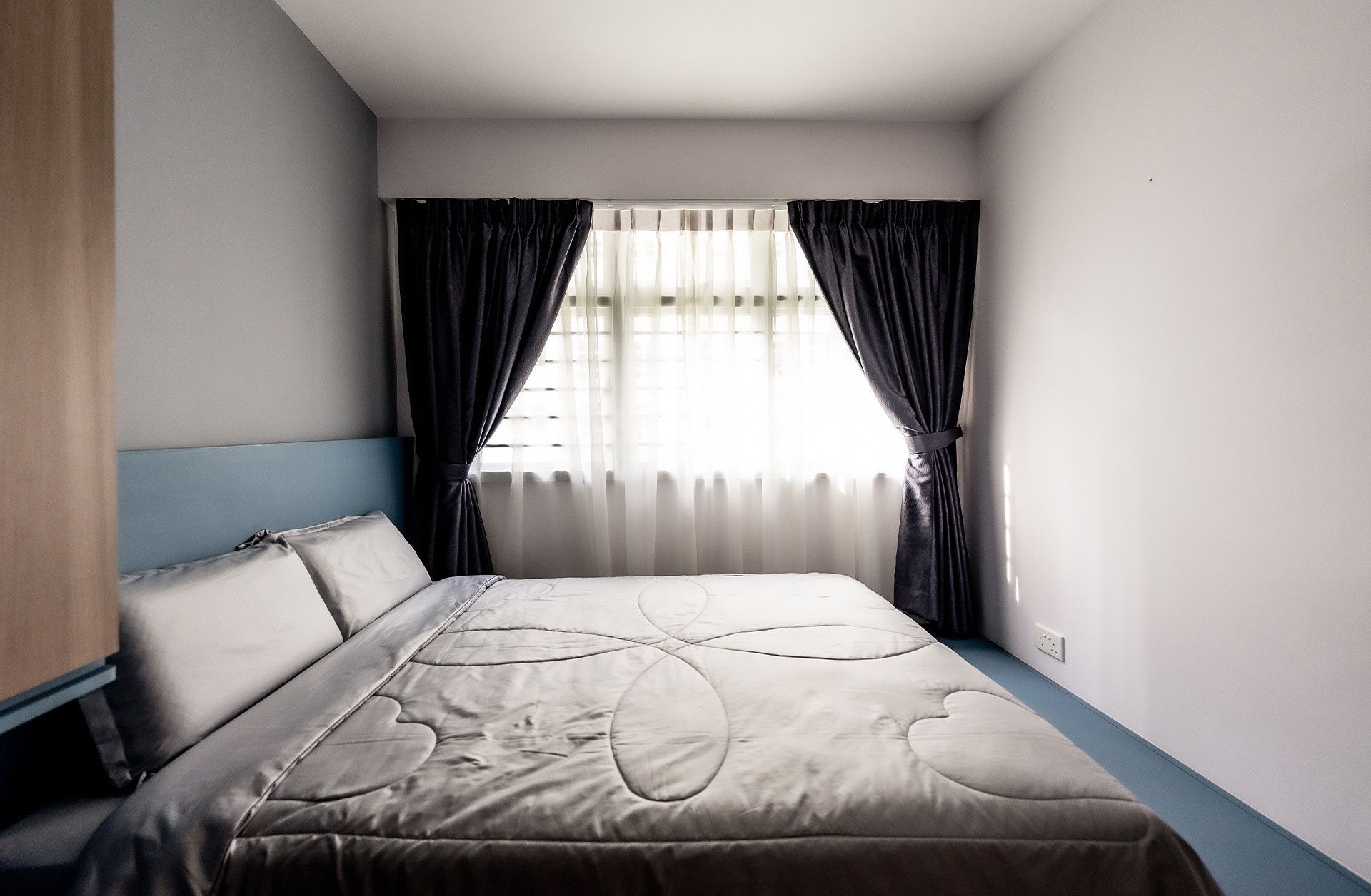 A bedroom with a bed and a window with black curtains