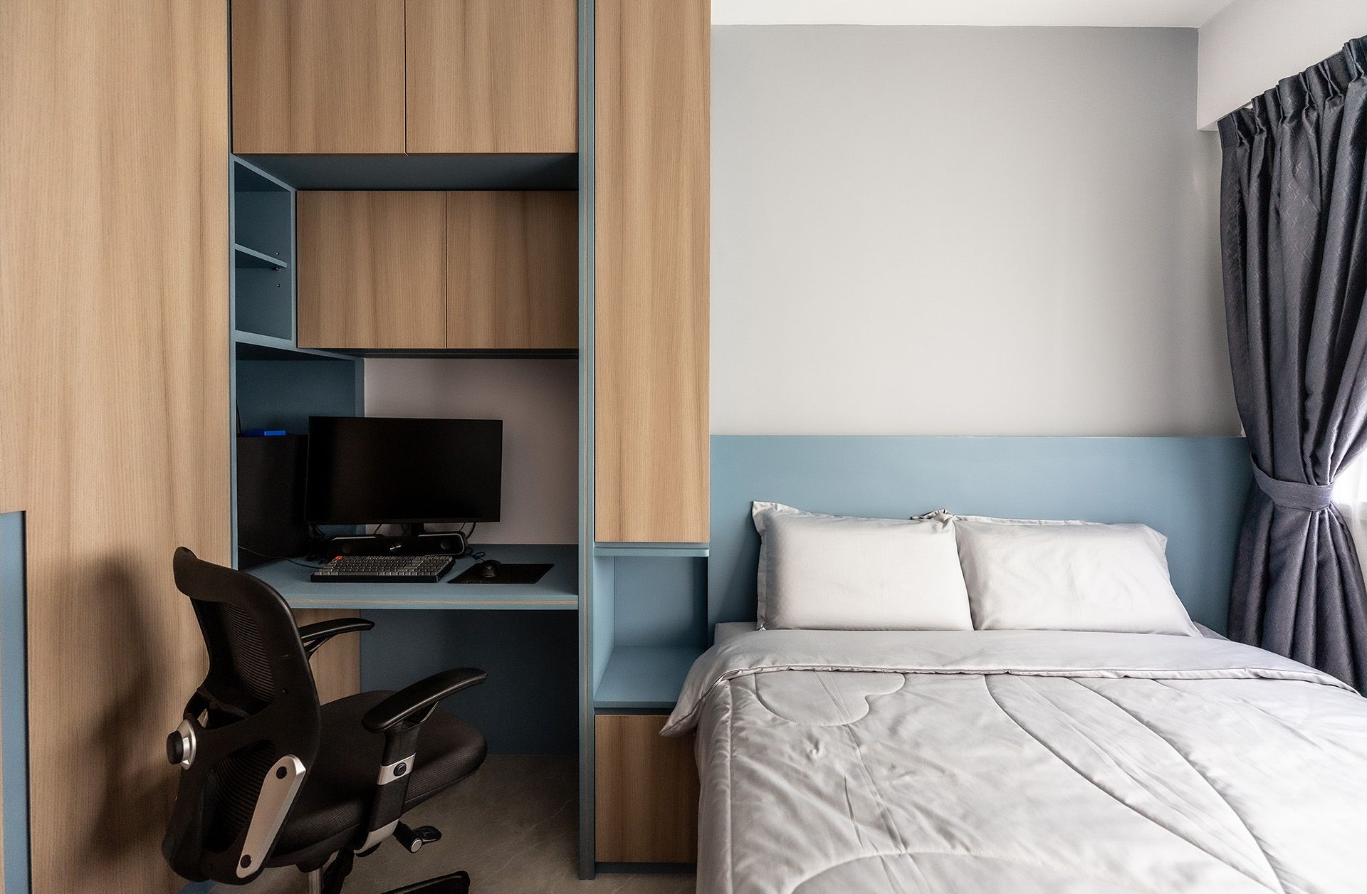 A bedroom with a bed , desk , chair and computer.