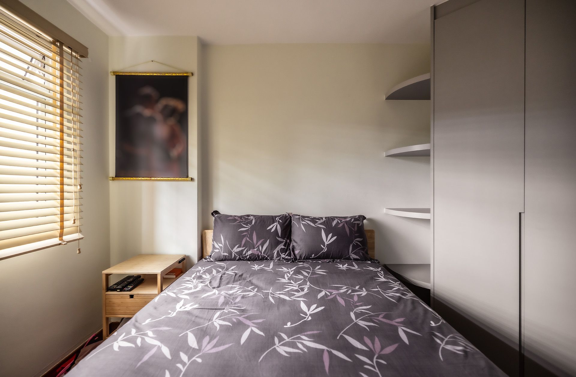 There is a painting on the wall above the bed in the bedroom.