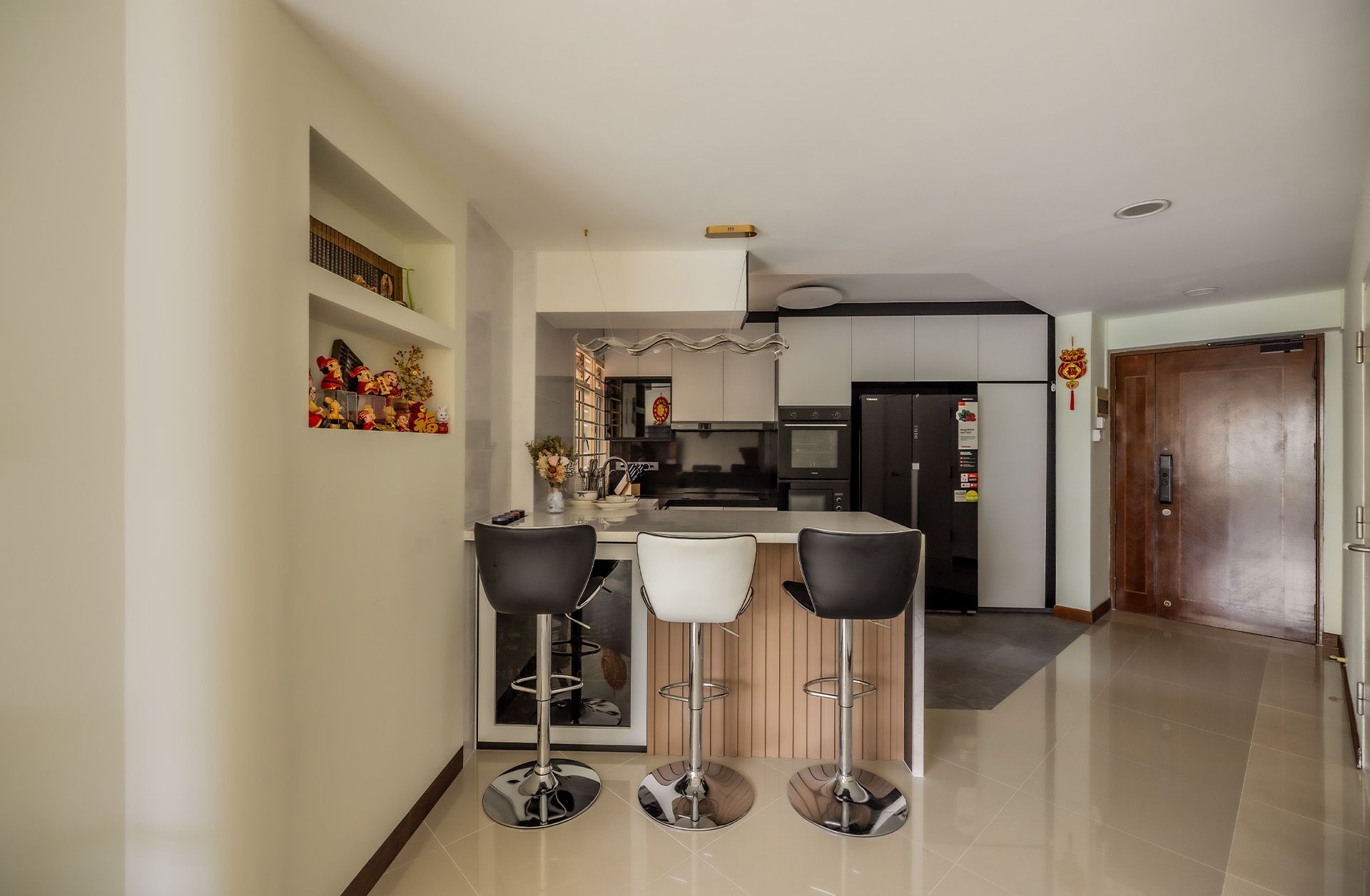 A kitchen with a bar and stools and a refrigerator.