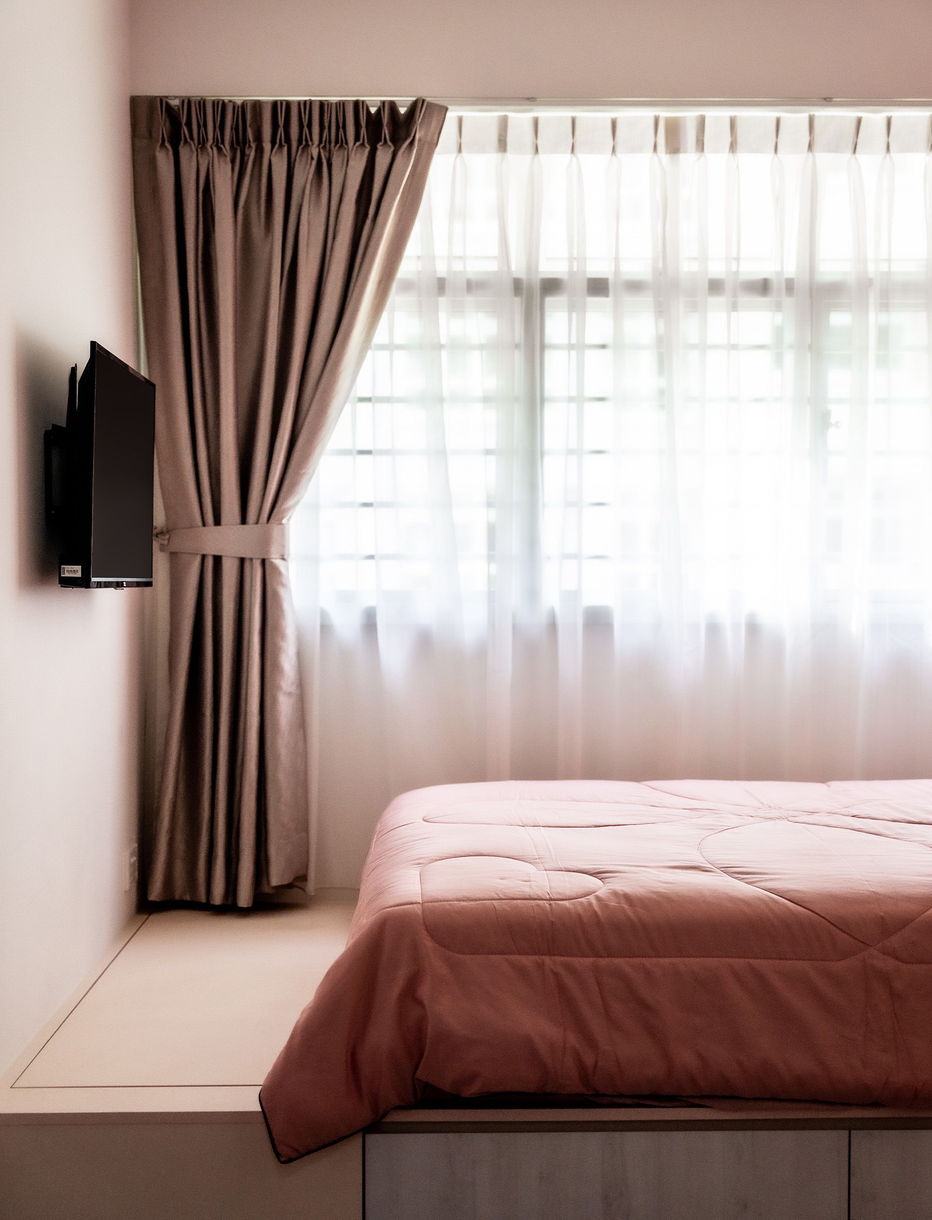 A bedroom with a bed and a television on the wall