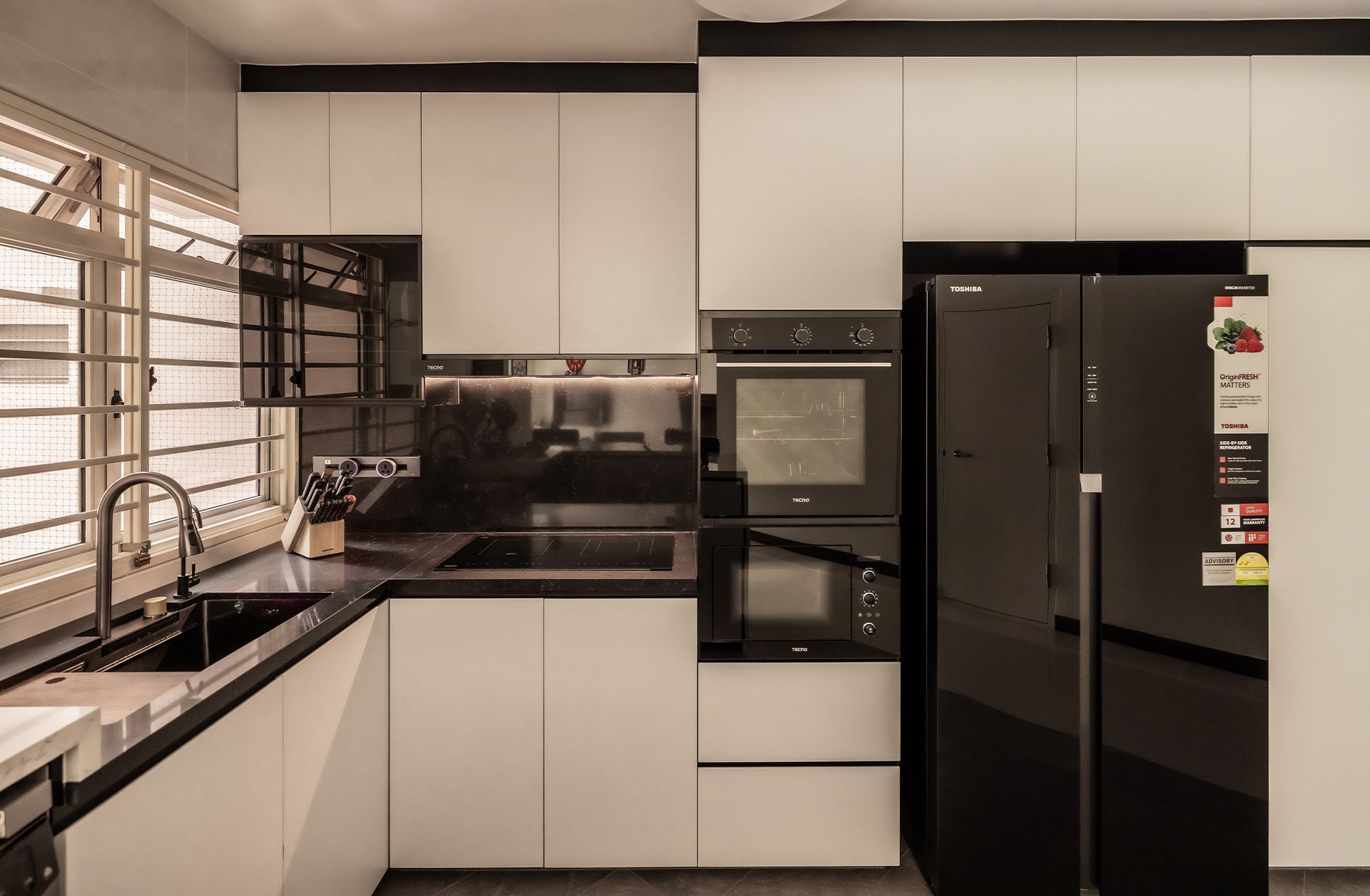 A kitchen with white cabinets and a black refrigerator.