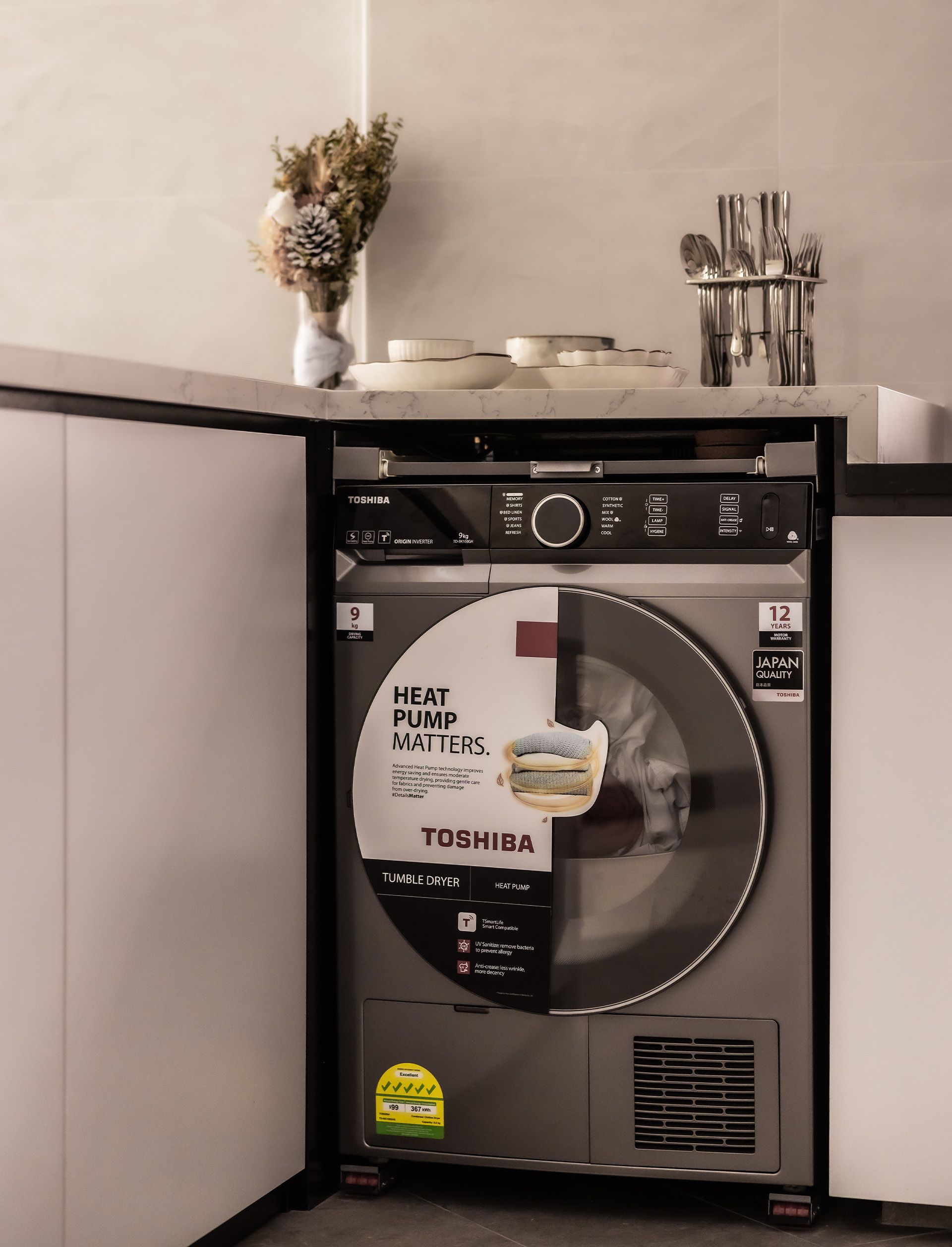 A toshiba washing machine is sitting on a counter in a kitchen.