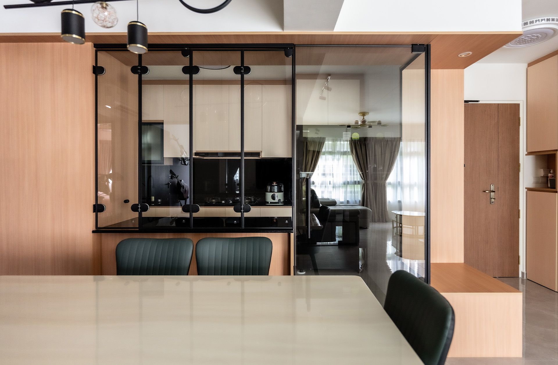 A dining room with a table and chairs and a kitchen in the background.