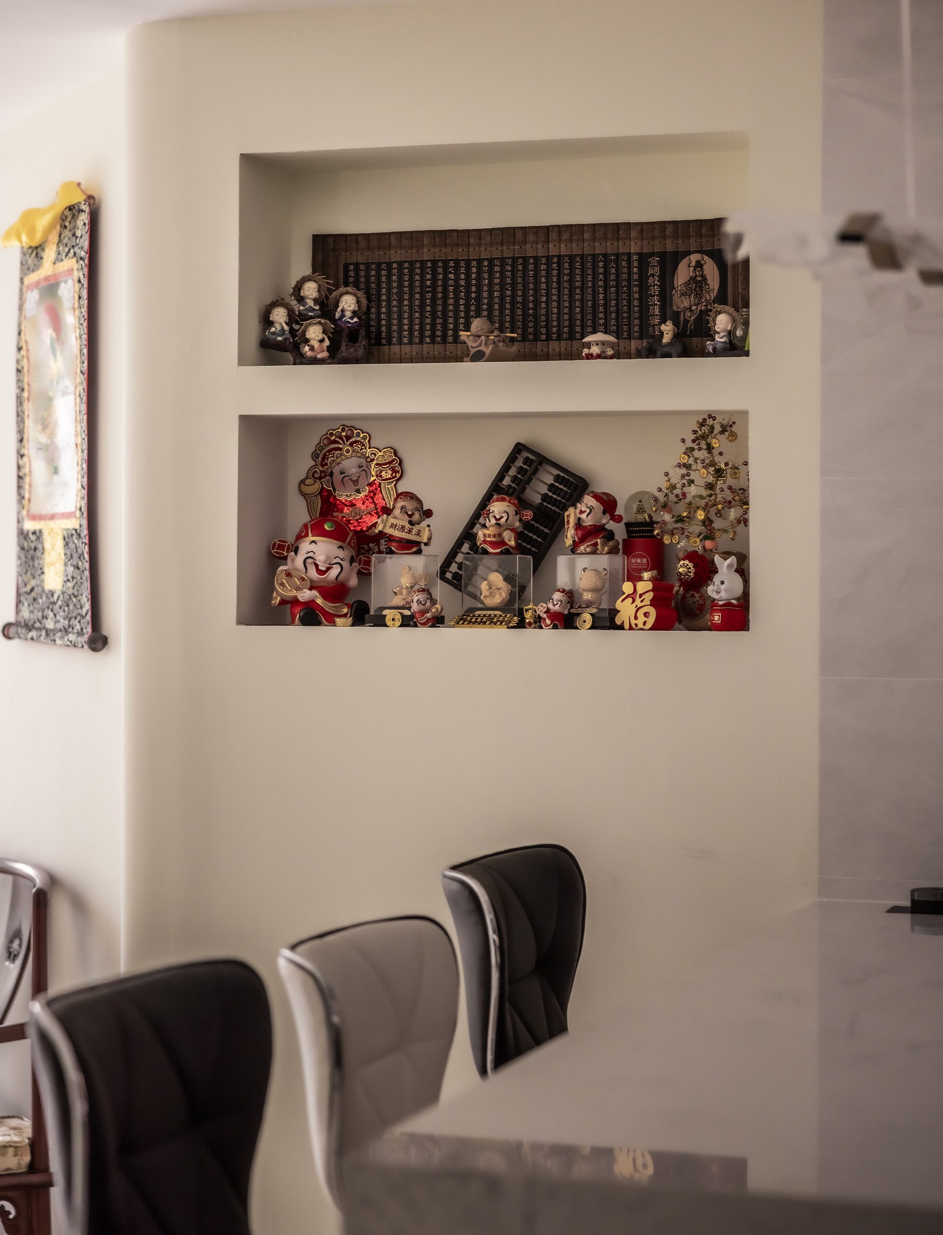 A dining room with a table and chairs and a shelf with toys on it.