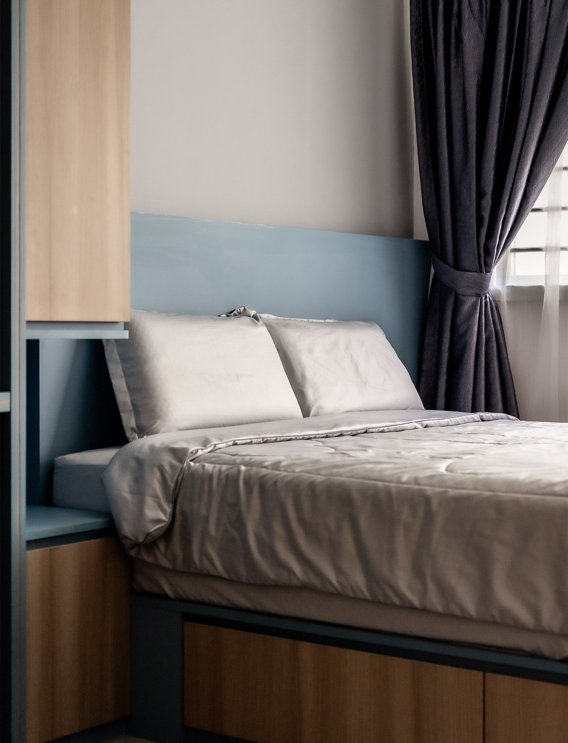A bed with white sheets and pillows in a bedroom next to a window.