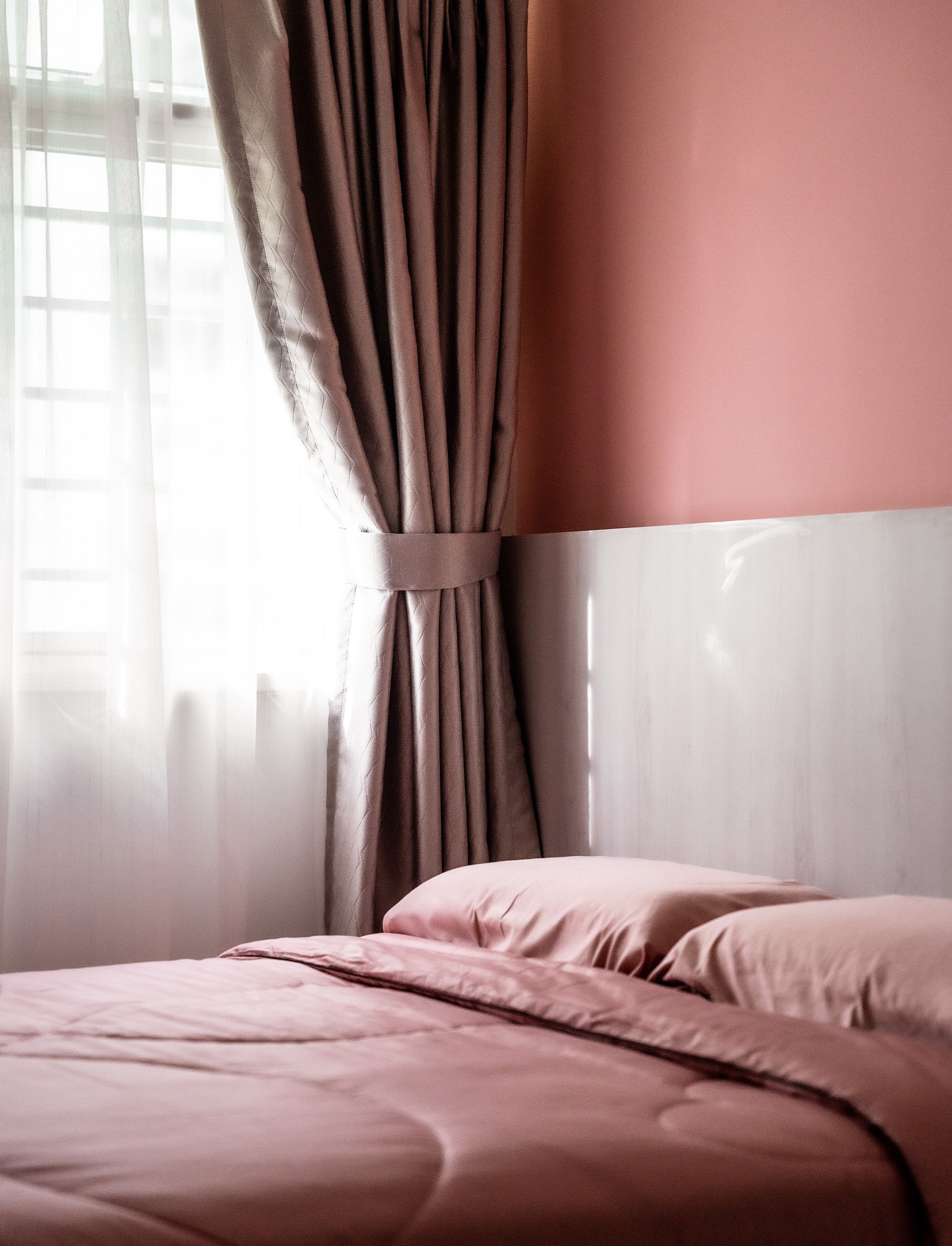 A bedroom with a bed , curtains and a window.