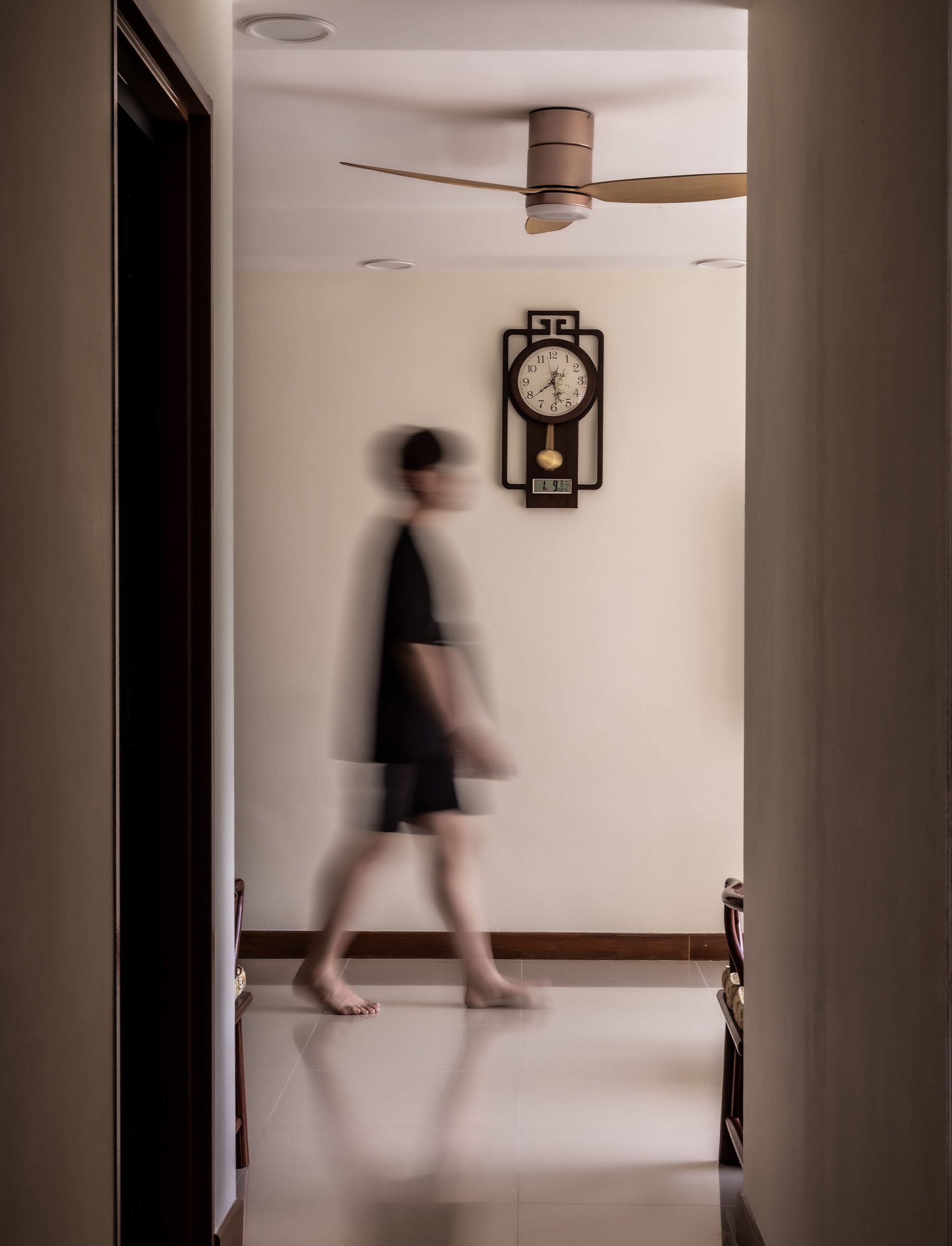 A blurry picture of a person walking in a hallway with a clock on the wall