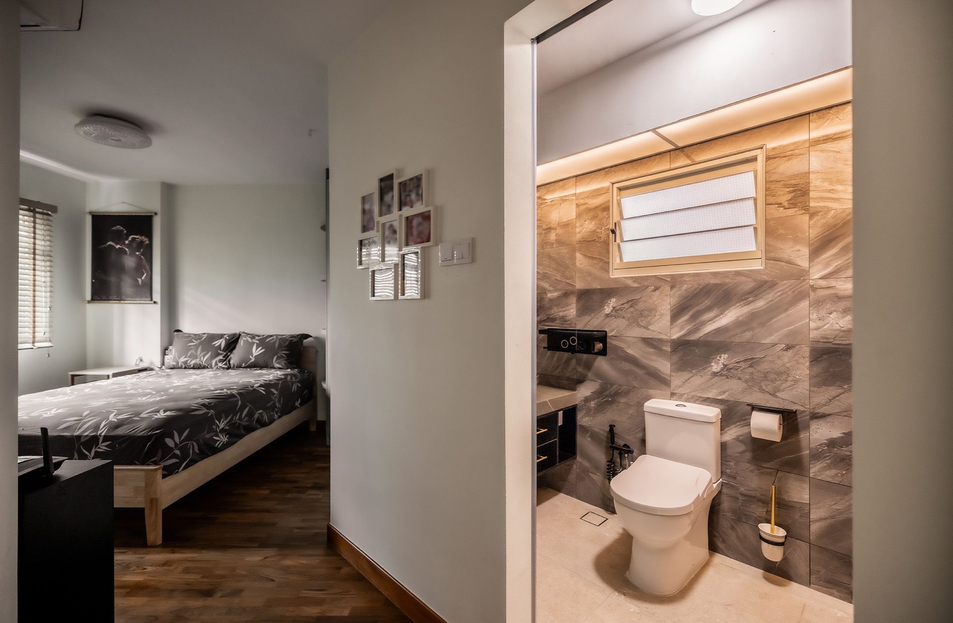 A bathroom with a toilet and a bed in the background.