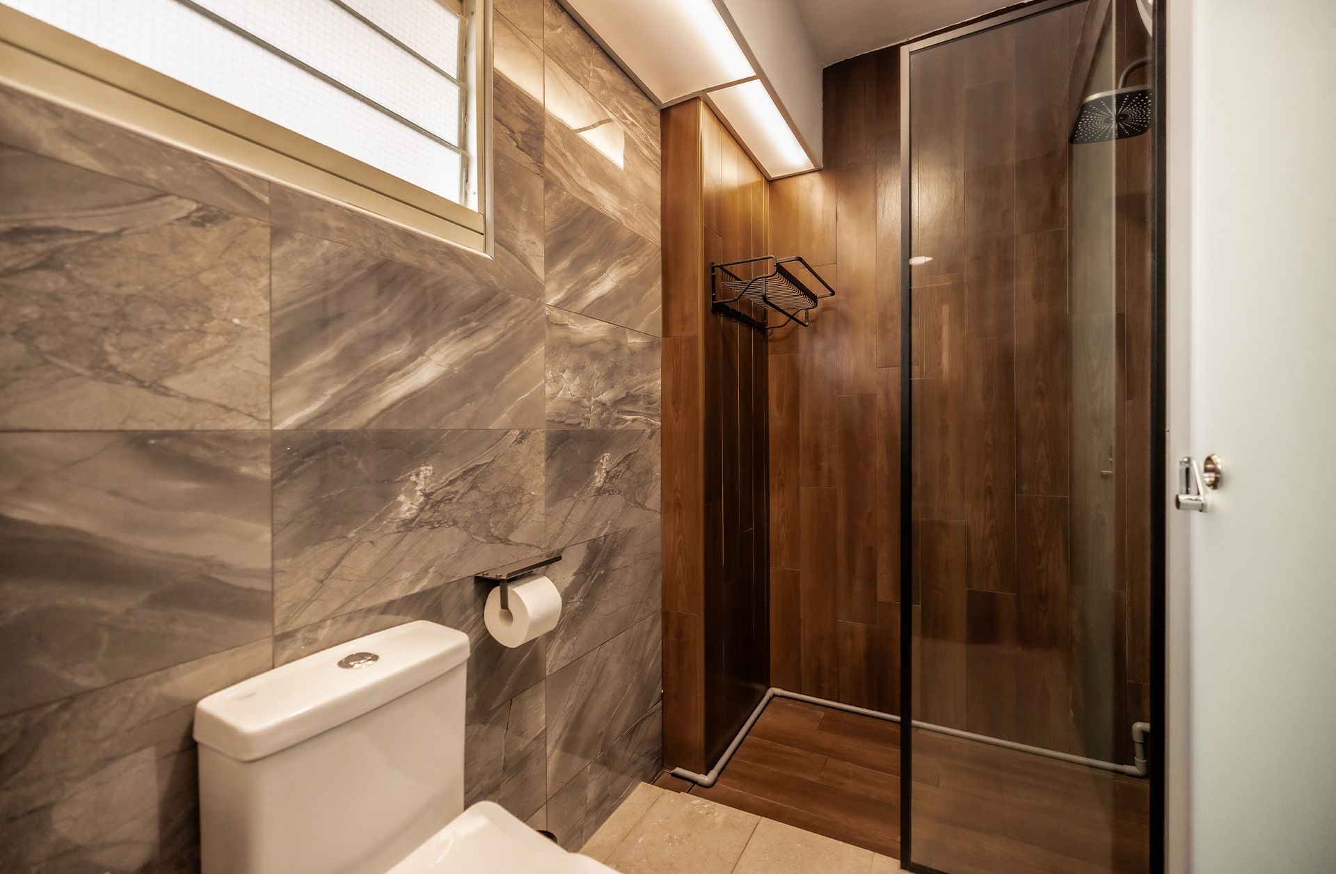 A bathroom with a toilet , shower and window.