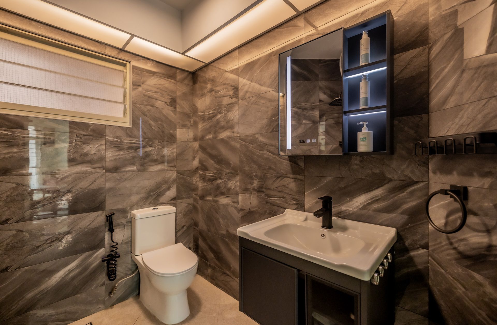 A bathroom with a toilet , sink and mirror.
