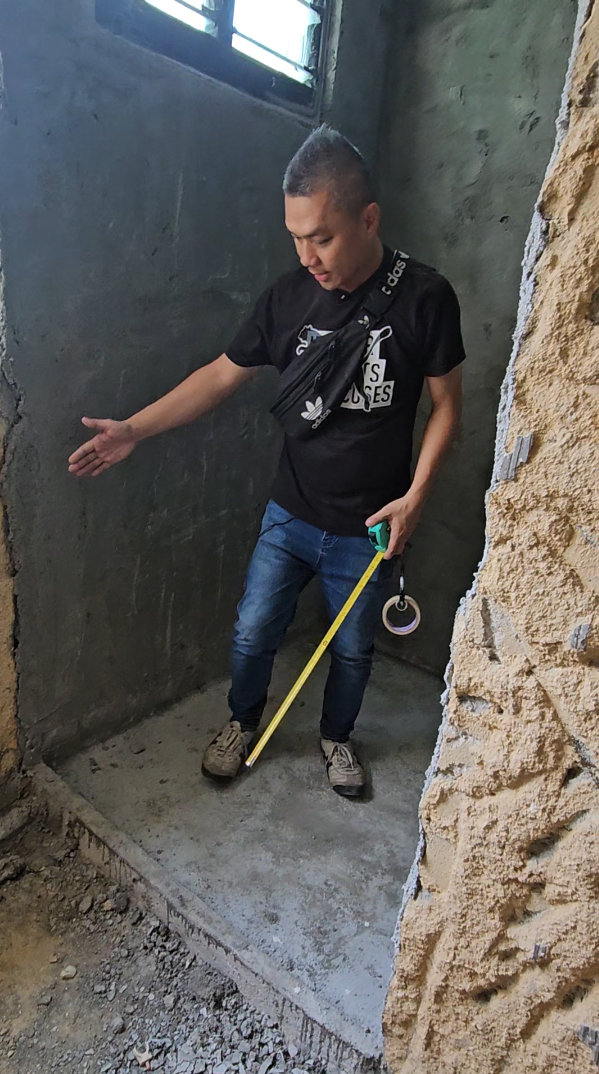 A man is standing in a room holding a tape measure.