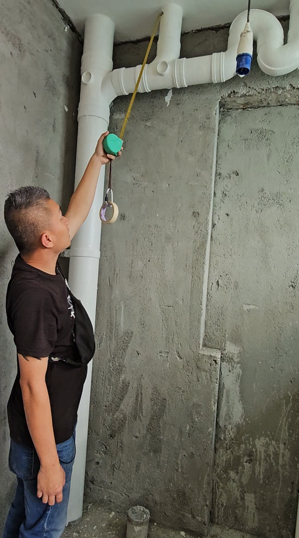 A man is measuring a pipe with a tape measure.