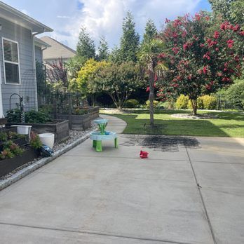 A concrete driveway with a table and chairs in front of a house.