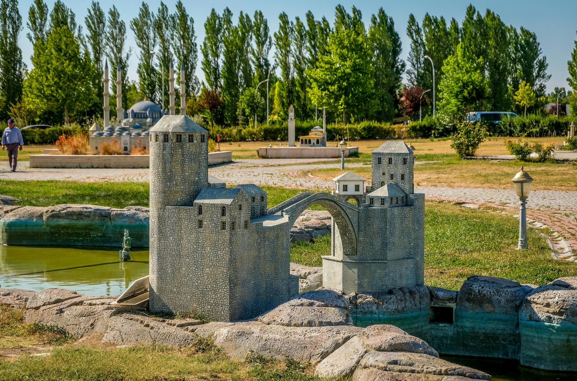 A model of a castle and a bridge in a park.