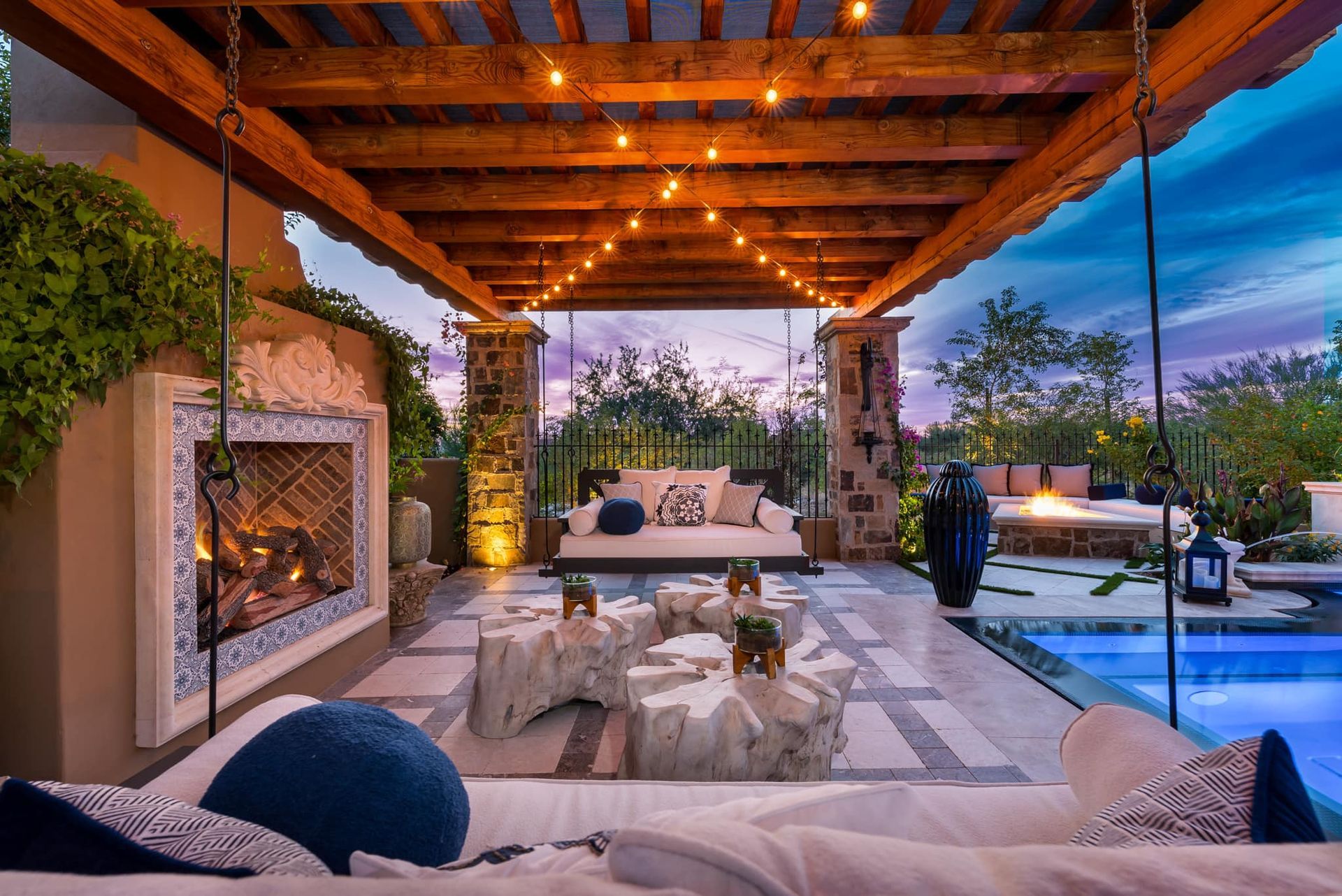 A patio with a fireplace and a swimming pool.